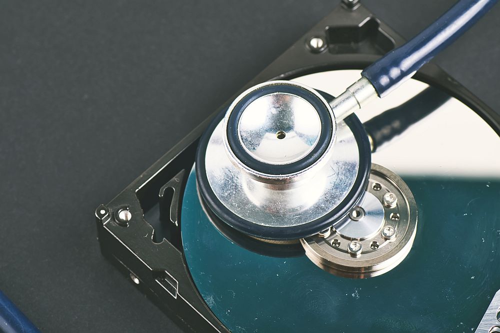 Data recovery or computer forensics concept, stethoscope dusty dismantle hard disk over dark background